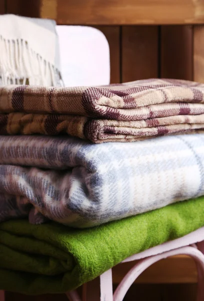 Warm plaids on chair on rustic wooden background — Stock Photo, Image