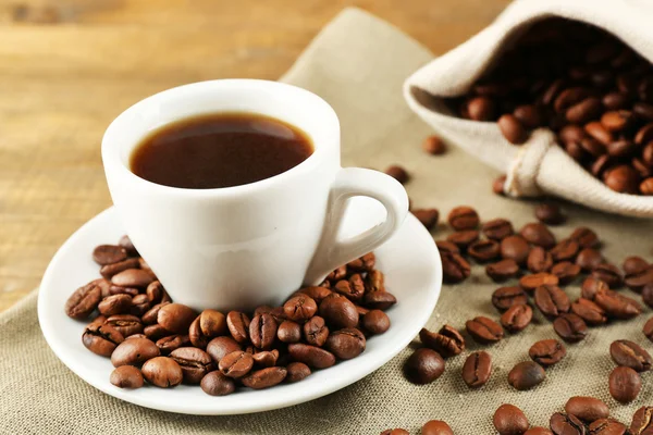 Taza de café con frijoles sobre fondo rústico de madera —  Fotos de Stock