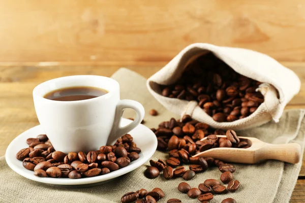 Taza de café con frijoles sobre fondo rústico de madera —  Fotos de Stock