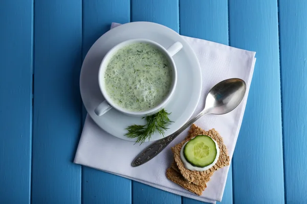 Cucumber soup in bowl on color wooden planks background — Stock Photo, Image