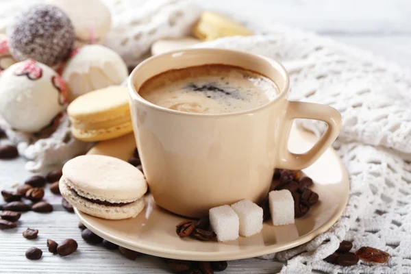 Mjuka färgglada macaroons och kaffe i mugg på träbord bakgrund — Stockfoto