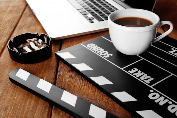 Film clapper avec ordinateur portable et tasse de café sur fond en bois — Photo