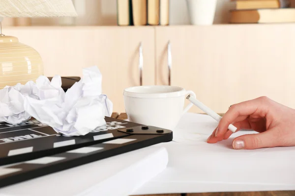 Female hand with cigarette at desktop with moving clapper and working mess on light cupboard background — Stock Photo, Image