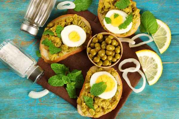 Sandwiches with green peas paste and boiled egg with napkin on color wooden background — Stock Photo, Image