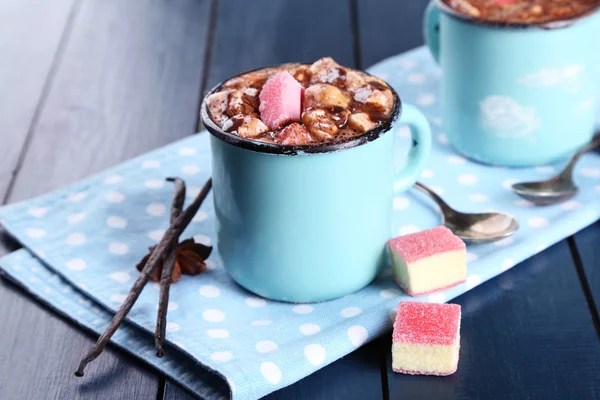 Tazze di caffè caldo con marshmallow su tovagliolo con zucchero grumo, anice stellato e bastoncini di vaniglia su sfondo tavolo di legno a colori — Foto Stock