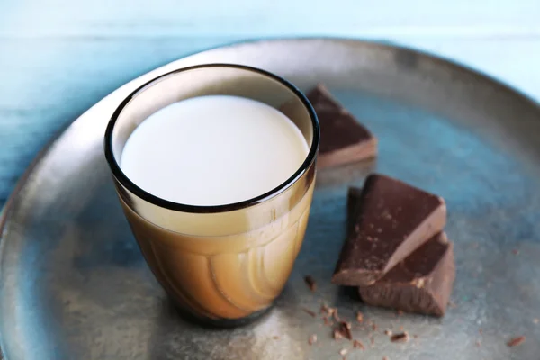 Bicchiere di latte con pezzi di cioccolato su vassoio di metallo e colore legno tavole sfondo — Foto Stock