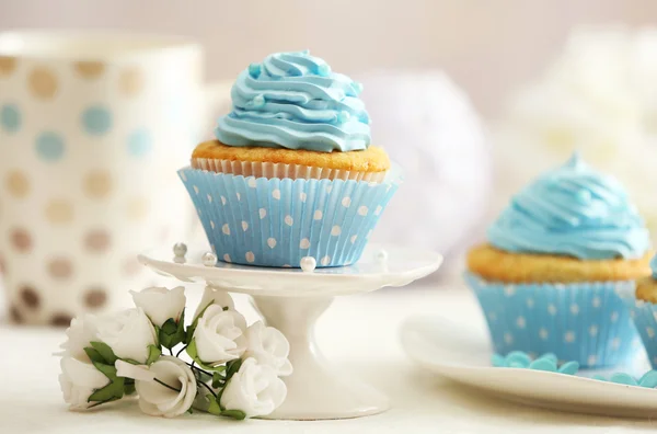 Deliciosos cupcakes en la mesa sobre fondo claro —  Fotos de Stock