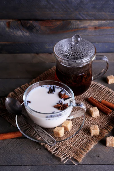 Tè nero con latte in vetreria e zucchero grumo su sfondo tavole di legno colore — Foto Stock