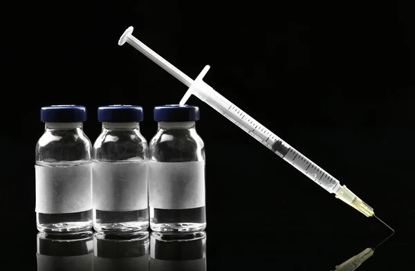 Ampules with syringe on black background — Stock Photo, Image