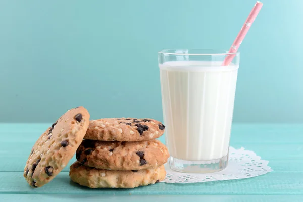 Tasty cookies and glass of milk on color wooden background — Stock Photo, Image