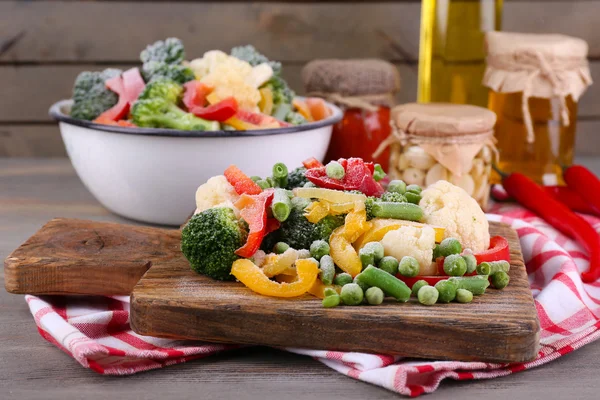 Frozen vegetables on cutting board, on napkin, on wooden table background — Stock Photo, Image