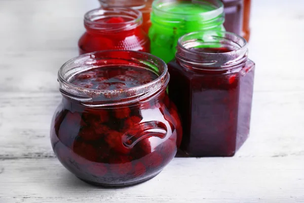 Homemade jars of fruits jam on color wooden planks background — Stock Photo, Image