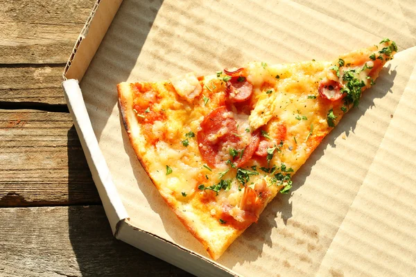 Last slice of pizza on wooden table — Stock Photo, Image