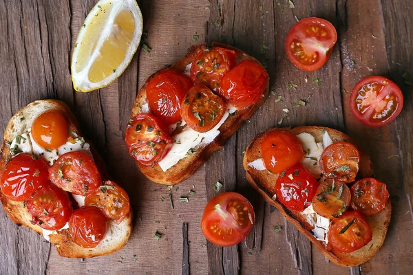 Tranches de pain blanc grillé avec tomates en conserve et citron vert sur fond de table en bois — Photo