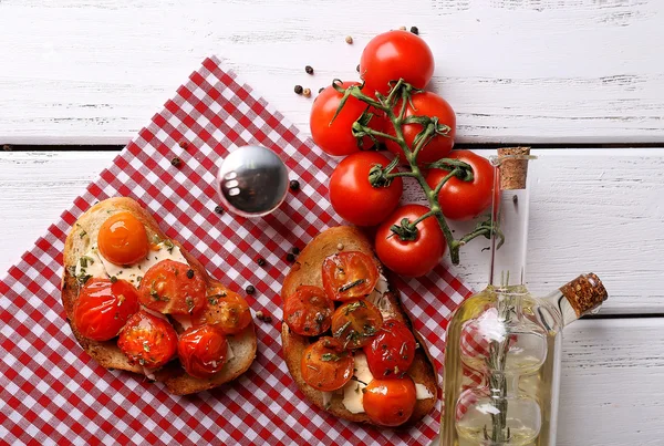 Fette di pane bianco tostato con burro e pomodori in scatola su fondo di legno — Foto Stock