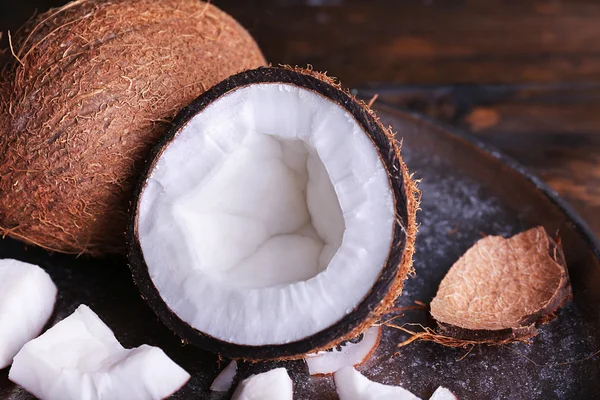 Gebarsten kokosnoot op metalen plaat op rustieke houten tafel achtergrond — Stockfoto