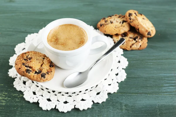 Cup of coffee and tasty cookie on color wooden background — Stock Photo, Image