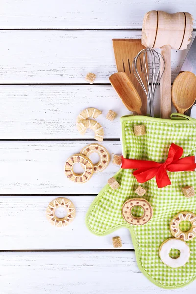 Conjunto de utensílios de cozinha com biscoitos em mitene sobre fundo de madeira — Fotografia de Stock