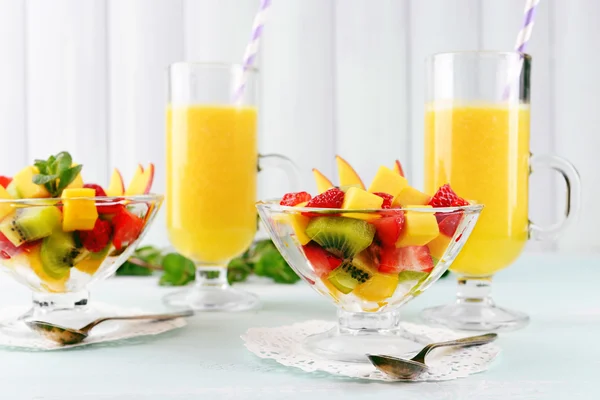 Фруктовый салат с мятой и апельсиновым соком в стеклянной посуде на деревянном столе и фоне досок — стоковое фото
