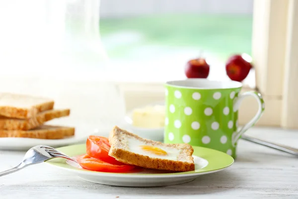 Huevo revuelto con pan en plato con taza de té sobre fondo brillante — Foto de Stock