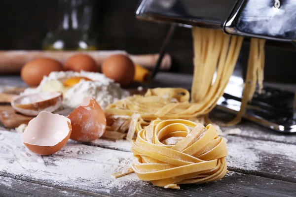 Máquina de hacer pasta de metal e ingredientes para pasta sobre fondo de madera — Foto de Stock