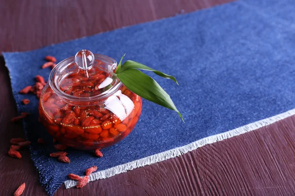 Jar of goji berry jam on napkin on wooden background — Stock Photo, Image
