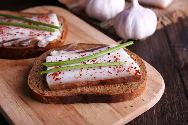 Smörgåsar med ister på skärbräda och vitlök på bordet på nära håll — Stockfoto
