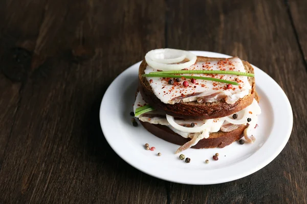 Sandwiches con manteca de cerdo y cebolla en plato sobre fondo de madera — Foto de Stock