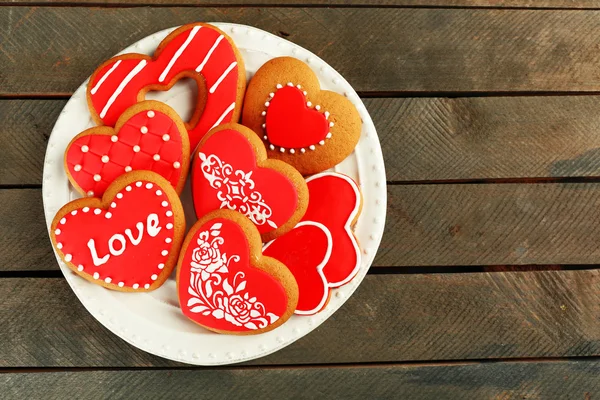 Cookies em forma de coração para dia dos namorados na placa, no fundo de madeira — Fotografia de Stock