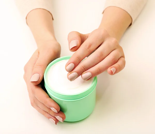 Mãos femininas segurando frasco de creme isolado no branco — Fotografia de Stock