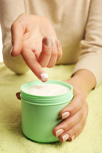 Vrouwelijke handen met potje crème op stof achtergrond — Stockfoto