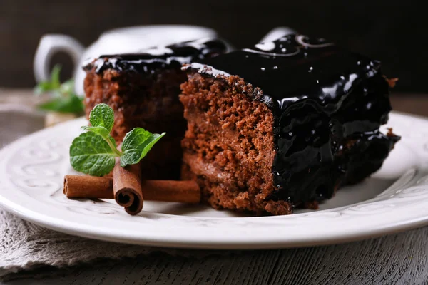 Pedaços saborosos de bolo de chocolate com hortelã e canela na mesa de madeira e fundo escuro — Fotografia de Stock