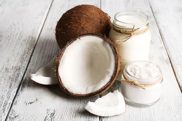 Aceite de coco fresco en cristalería sobre fondo de mesa de madera de color — Foto de Stock