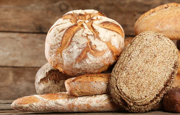 Verschillende vers brood op oude houten tafel — Stockfoto