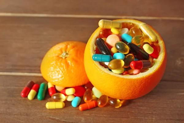オレンジ色の果物や木製の背景上のカラフルな錠剤 — ストック写真