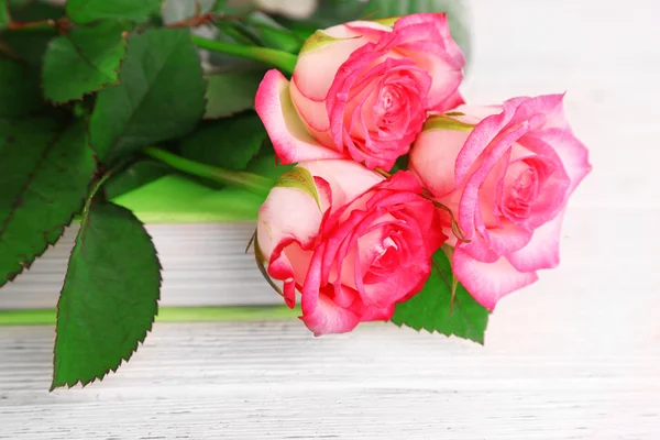 Bellissime rose con libro sul tavolo di legno, primo piano — Foto Stock