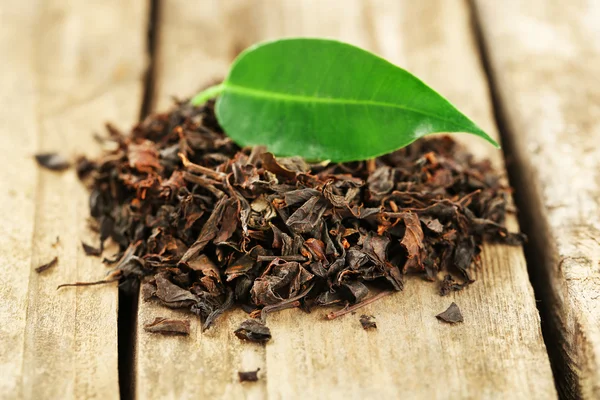 Té negro con hoja sobre mesa de madera vieja —  Fotos de Stock