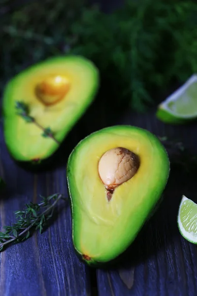 Gesneden avocado met limoen en kruid op houten tafel, close-up — Stockfoto