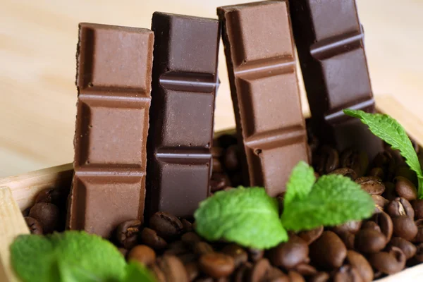 Still life with set of chocolate in wooden box of coffee grains, closeup — Stock Photo, Image