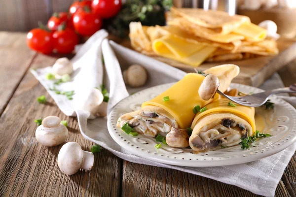 Pannenkoeken met romige paddestoelen in plaat op houten tafel, close-up — Stockfoto