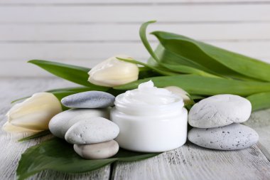 Çiçek ve spa taşlar ahşap arka plan üzerinde kozmetik krem