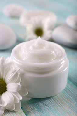 Çiçek ve spa taşlar ahşap arka plan üzerinde kozmetik krem