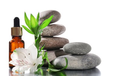 Spa taşlarla aromatik yağlar ve üzerinde beyaz izole çiçek