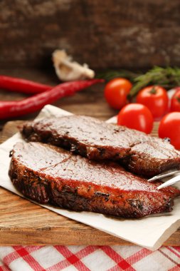 Lezzetli kızarmış et kesme tahtası, domates ve ahşap zemin üzerine biberiye dal ile kompozisyon