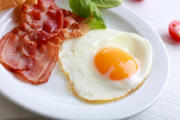 Bacon and eggs on color wooden table background — Stock Photo, Image