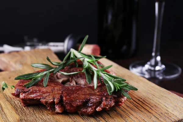 Steak grillé avec bouteille de vin sur fond sombre — Photo