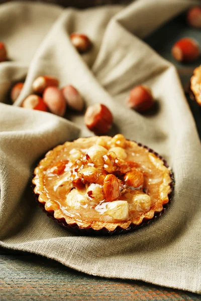 Mini torta con noci su tovagliolo su sfondo di legno — Foto Stock