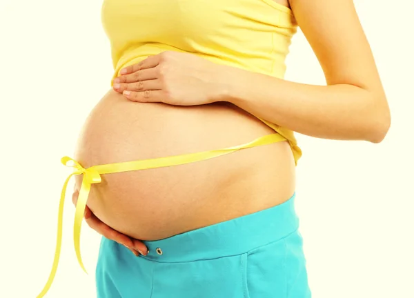 Mooie jonge zwangere vrouw aanraken haar buik op lichte achtergrond — Stockfoto