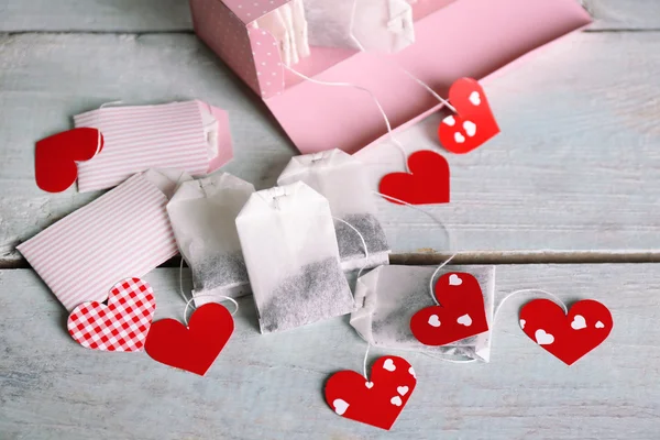 Чайный мешок в форме сердца и коробка на деревянном фоне — стоковое фото