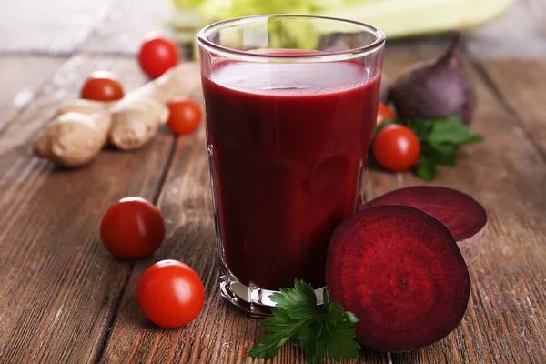 Glass of beet juice with vegetables on wooden table close up — Stock Photo, Image